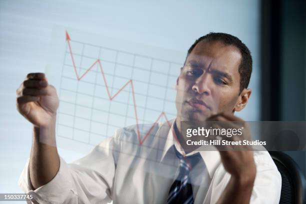 異人種のビジネスマンが見折れ線グラフ - エコノミスト ストックフォトと画像