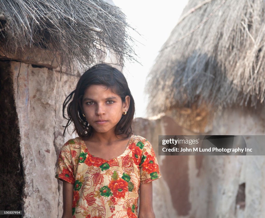 Serious Indian girl near thatched hut, Rajasthan India
