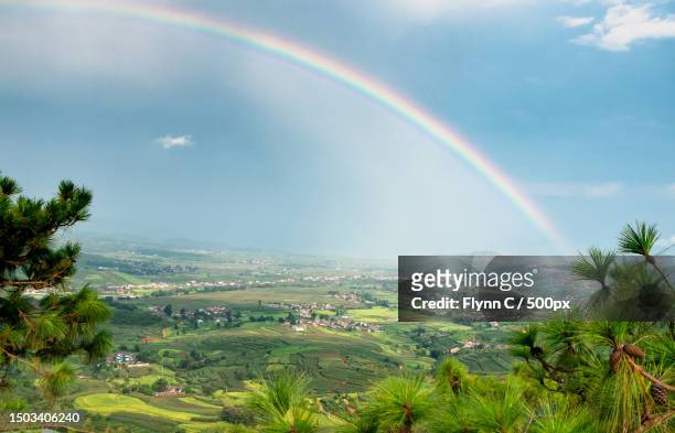 scenic view of rainbow over landscape against sky,sichuan provice,china - rainbow mountains china stockfoto's en -beelden
