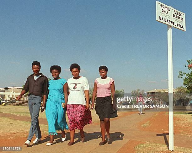 Black people pass a segregation sign, setting aside seperate areas for blacks and whites, 01 September1989 in the town of Carltonville.