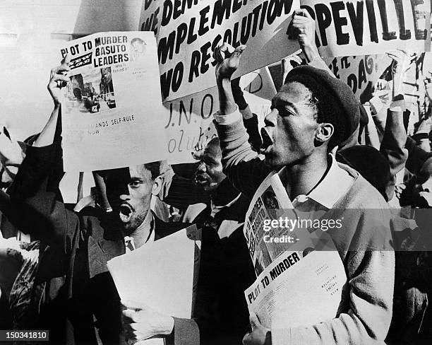 Demonstrators hold placards and shout slogans against apartheid segregation policy outside the hotel where Secretary General of the United Nations...