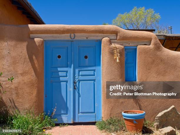 blue doorway contrasts with earth toned adobe church building in rancho de taos new mexico - adobe texture stock pictures, royalty-free photos & images