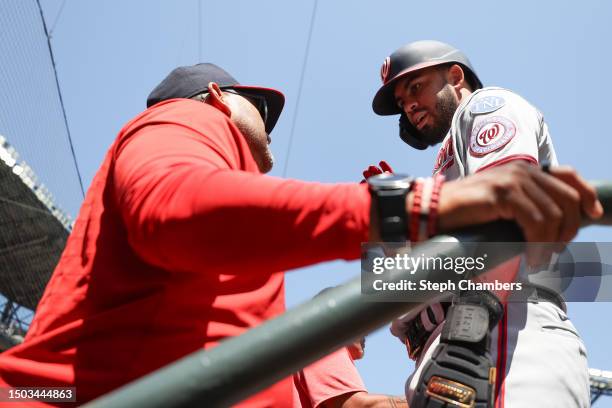 Manager Dave Martinez congratulates Luis Garcia of the Washington Nationals after his run during the first inning against the Seattle Mariners at...