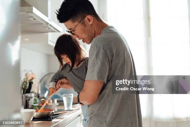 young asian father and daughter cooking together in kitchen at home - adopted chinese daughter ストックフォトと画像