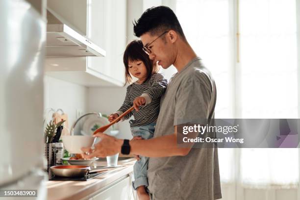 young asian father and daughter cooking together in kitchen at home - asian father and daughter stock pictures, royalty-free photos & images