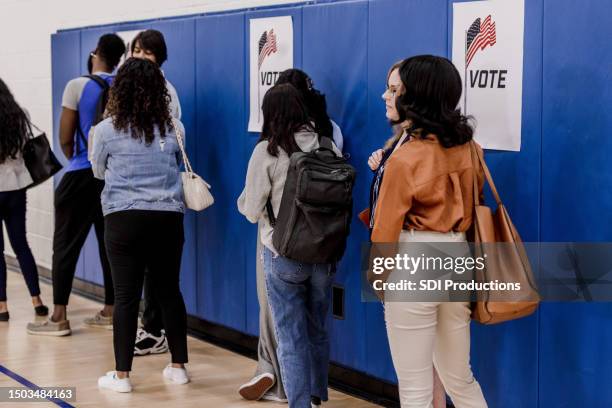 multiracial group of voters stand in line at the polling place - looking from rear of vehicle point of view stock pictures, royalty-free photos & images