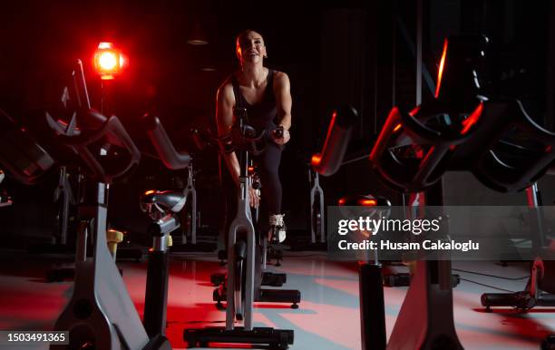 athlete woman training on stationary bike in fitness gym. - spin class stock pictures, royalty-free photos & images