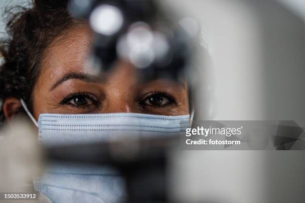 close up shot of female scientist putting a microscope slide under a microscope and smiling at camera - ecuadorian ethnicity stock pictures, royalty-free photos & images