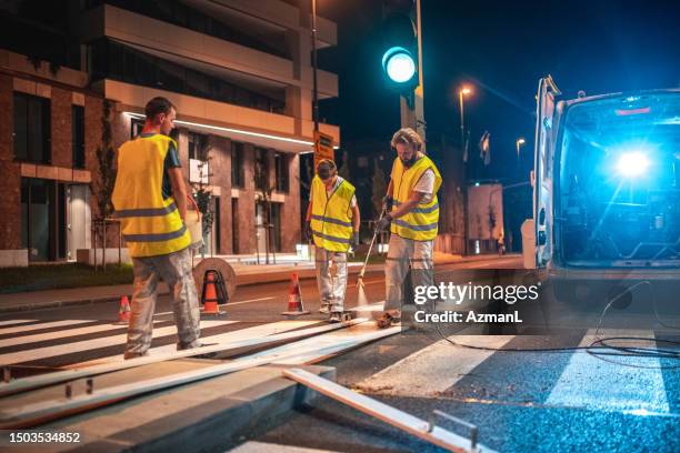 spray painting a crosswalk with a spray gun - roadworks stock pictures, royalty-free photos & images