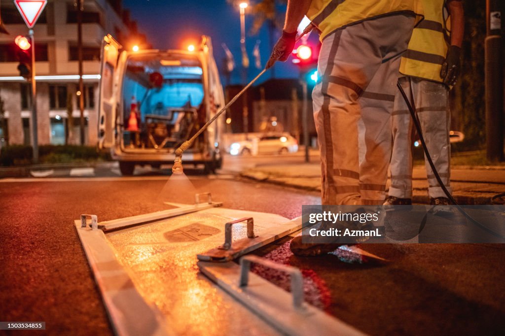 Road Maintenance Crew Spray Painting A Turn Right Road Sign