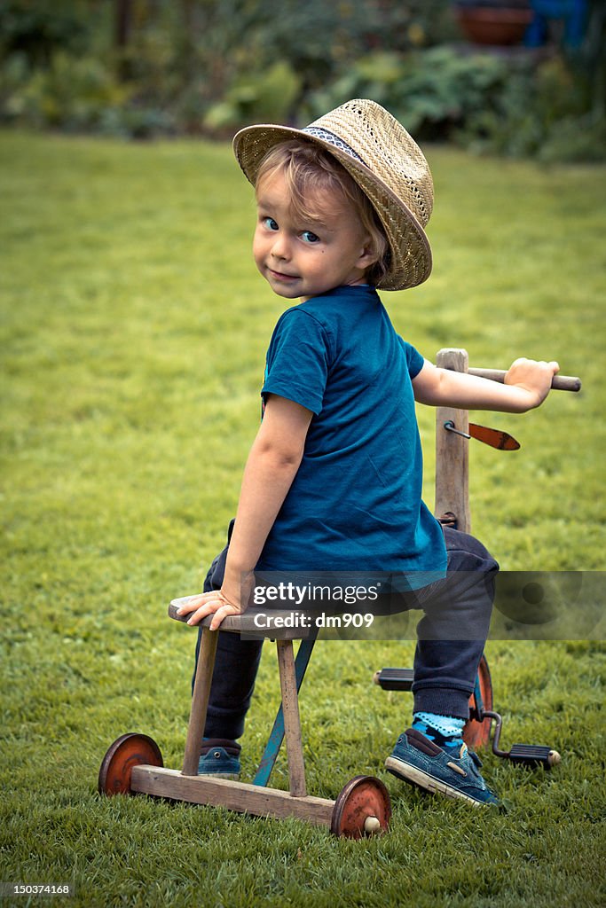 Boy with hat siting on vintage tricycle