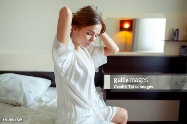 young woman sitting on bed in pajamas - this morning 2017 ストックフォトと画像