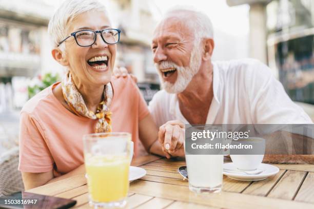 senior couple in sidewalk cafe - happy mature couple laugh stock pictures, royalty-free photos & images