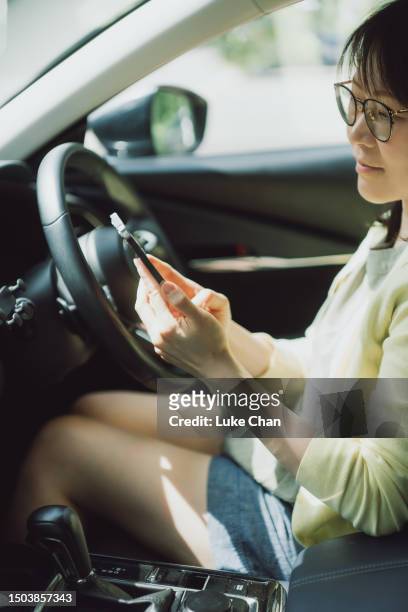 asian woman using smartphone in a car - front passenger seat stock pictures, royalty-free photos & images