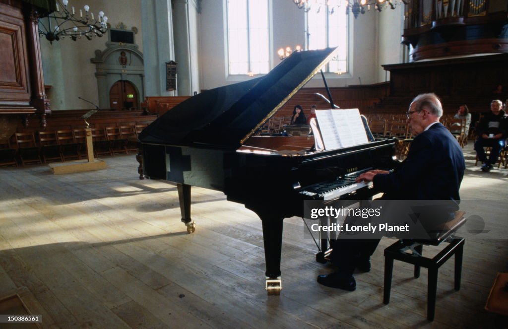 Pianist playing inside Calvinist Baroque church Noordekerk.