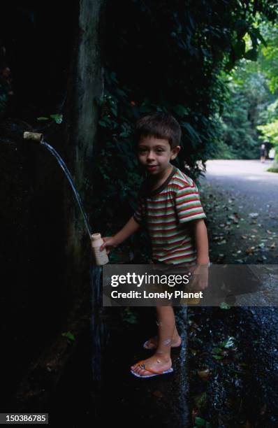 boy collecting water from fountain at paineiras, floresta da tijuca. - lonely planet collection foto e immagini stock