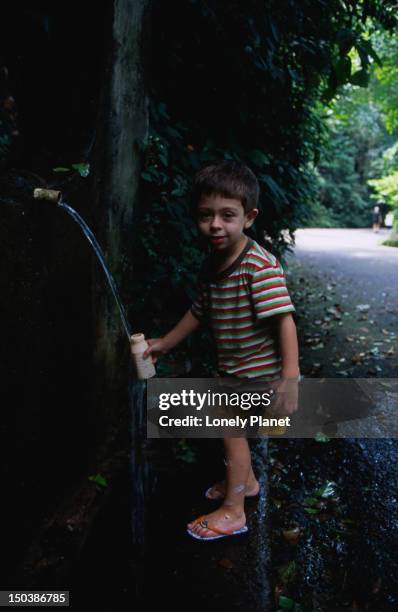 boy collecting water from fountain at paineiras, floresta da tijuca. - lonely planet collection stock pictures, royalty-free photos & images