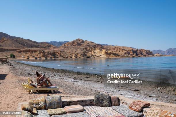 tourists relaxing in the sun at a camp in sinai beside the gulf of aqaba - nuweiba beach stock pictures, royalty-free photos & images