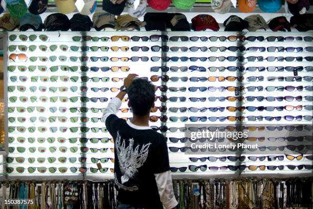 customer at sunglass stall at kata beach evening market. - lonely planet collection foto e immagini stock