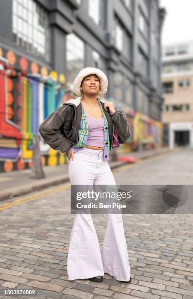 portrait of woman standing on city street - baggy pants stock pictures, royalty-free photos & images