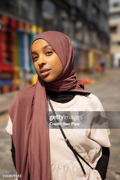portrait of young woman wearing hijab on street - hoofd schuin stockfoto's en -beelden