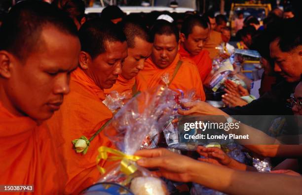 monks collecting alms at merit-making ceremony in gardens of sanam luang as part of thai new year celebrations of songkran festival. - lonely planet collection foto e immagini stock