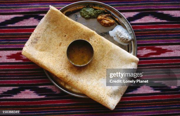 masala dosa - a south indian pancake made from a lentil flour and water batter and stuffed with mashed potato and spices - thosai stock pictures, royalty-free photos & images