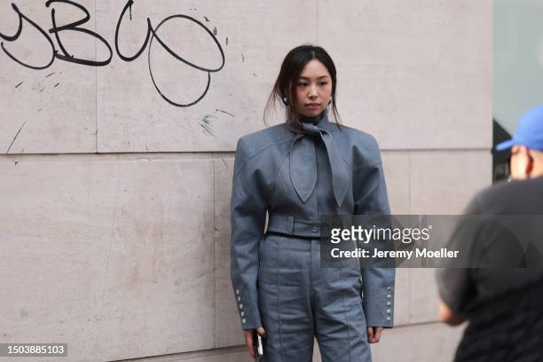 Guest is seen wearing a jumpsuit in jeans optic with a big belt and big bow as a collar in the same material with silver buttons and blue and silver...