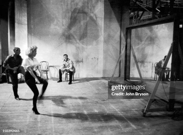 Jack Cole instructing Marilyn Monroe while Yves Montand smokes cigarette in background. For the film 'Let's Make Love', 1960.