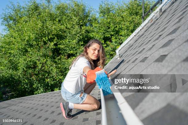 woman cleaning his house roof gutters - cleaning gutters stock pictures, royalty-free photos & images