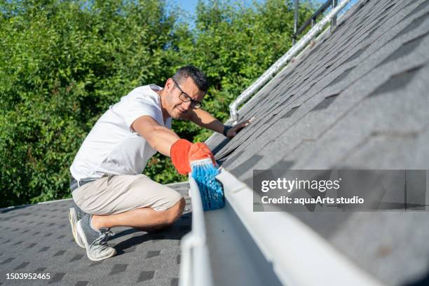 homem limpando as calhas do telhado de sua casa - eaves - fotografias e filmes do acervo