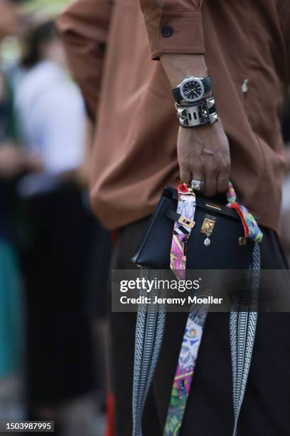 Fashion Week guest is seen wearing a brown cowboy hat, brown buttoned flannel jacket, black pants, Patek Philippe watch, Hermes black leather mini...