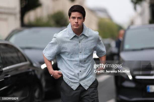 Blake Grey is wearing a blue button shirt with short sleeves and black pants with white sneakers outside Amiri Show during the Menswear Spring/Summer...