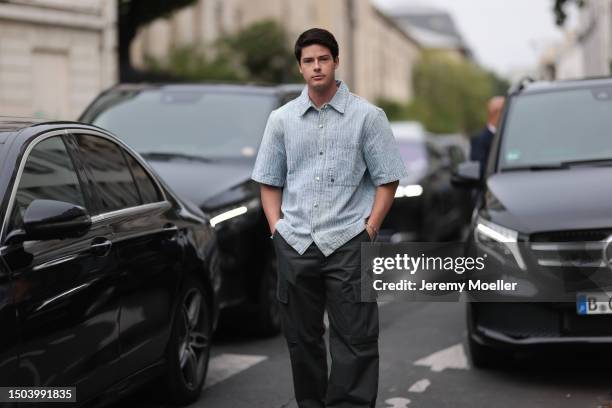 Blake Grey is wearing a blue button shirt with short sleeves and black pants with white sneakers outside Amiri Show during the Menswear Spring/Summer...