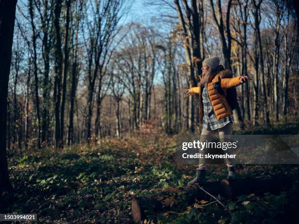 happy female hiker walking on tree trunk in autumn day. - fall park stock pictures, royalty-free photos & images