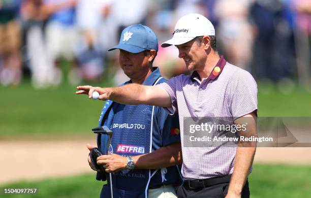 Justin Rose of England talks with his caddie on the 9th hole during Day One of the Betfred British Masters hosted by Sir Nick Faldo 2023 at The...