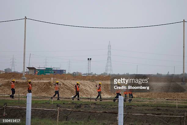 Workers walk towards a construction site in Sanand, Gujarat, India, on Wednesday, Aug. 8, 2012. India’s growth slowed to 5.3 percent in the three...