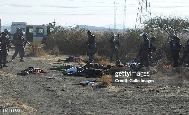 Police officers check bodies lying on open ground after opening fire on striking mine workers outside the Nkageng informal settlement on August 16,...