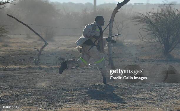 Striking mine worker runs for cover after police officers open fire outside the Nkageng informal settlement on August 16, 2012 in Marikana, South...