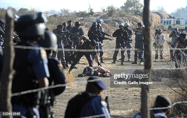 Police officers check bodies lying on open ground after opening fire on striking mine workers outside the Nkageng informal settlement on August 16,...