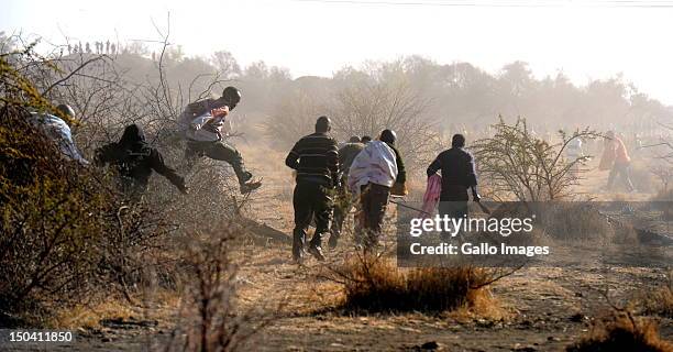 Striking mine workers run for cover after police officers open fire outside the Nkageng informal settlement on August 16, 2012 in Marikana, South...