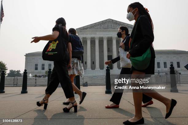 Group of people wear face masks to protect against air pollution as they walk past the U.S. Supreme Court Building on June 29, 2023 in Washington,...