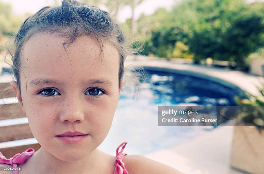 Young girl next to a pool, looking to camera