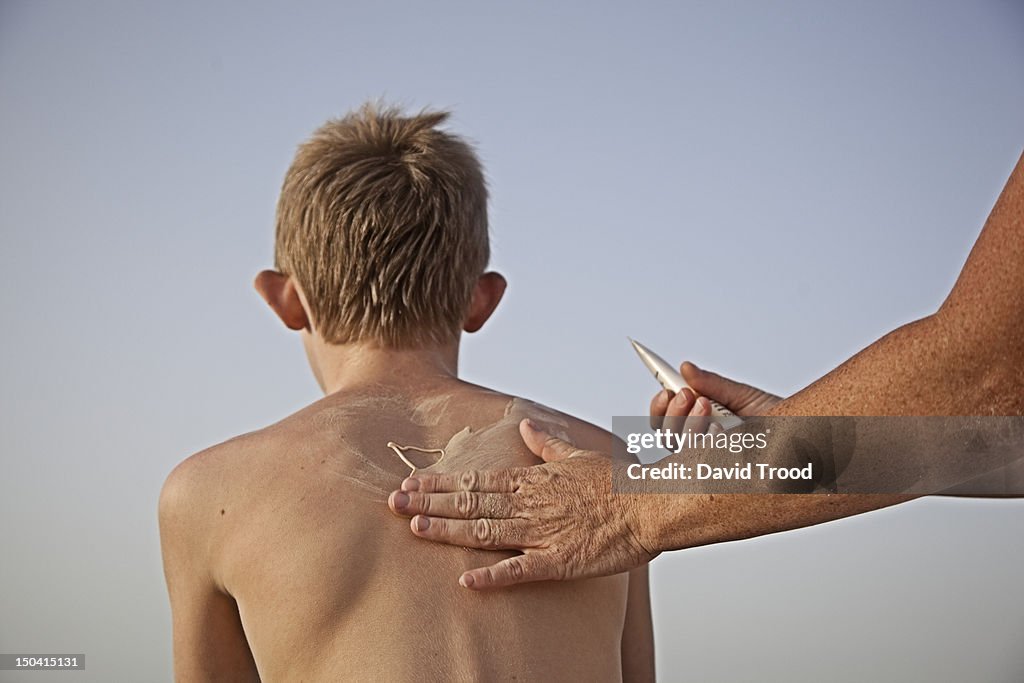 Mother putting sun cream on her son.