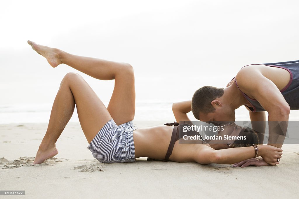 A man and woman kissing on a beach.