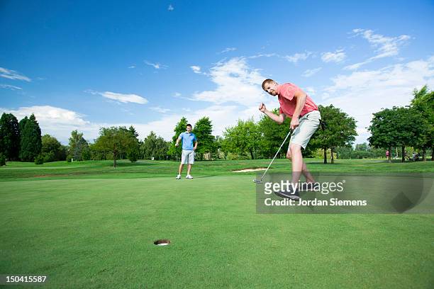two men golfing on a sunny summer day. - golfer putting stock pictures, royalty-free photos & images