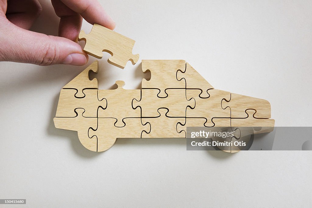 Wooden car jigsaw puzzle, final piece being placed