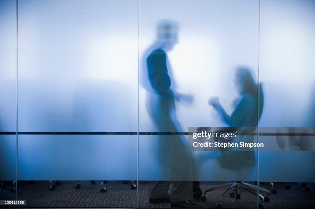 Executives confer behind frosted glass