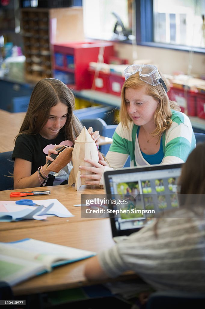 Girls [11] in classroom working on model rocket