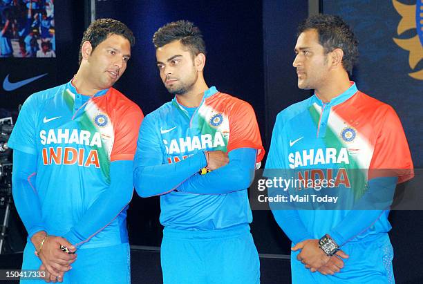 Indian team cricket players Yuvraj Singh, Virat Kohli, and captain Mahendra Singh Dhoni, pose for photographer during the launch of their new team...